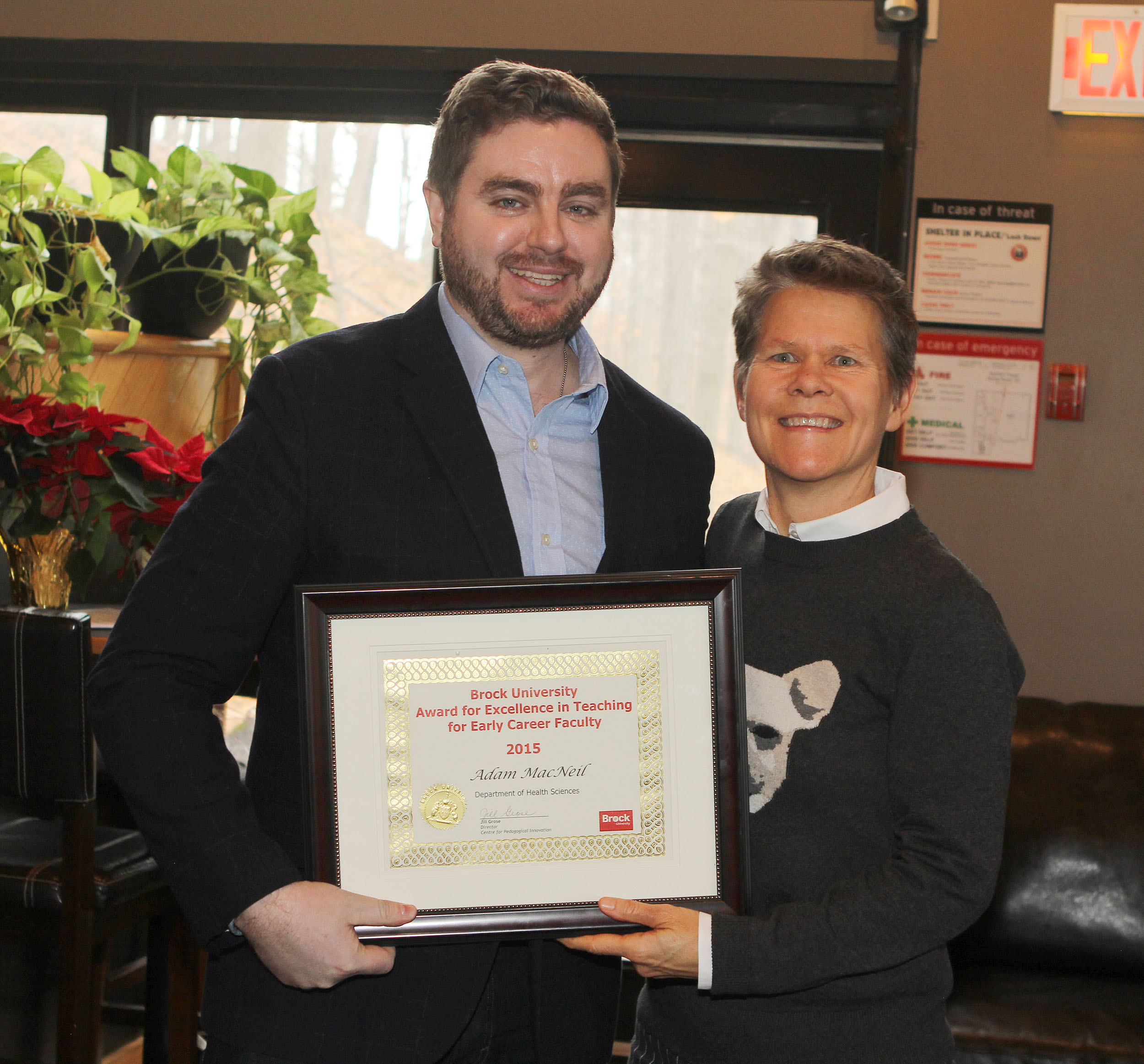 Dr. Adam MacNeil receiving the 2015 Brock University Award for Excellence in Teaching for Early Career Faculty from Dr. Paula Gardner the 2014 recipient